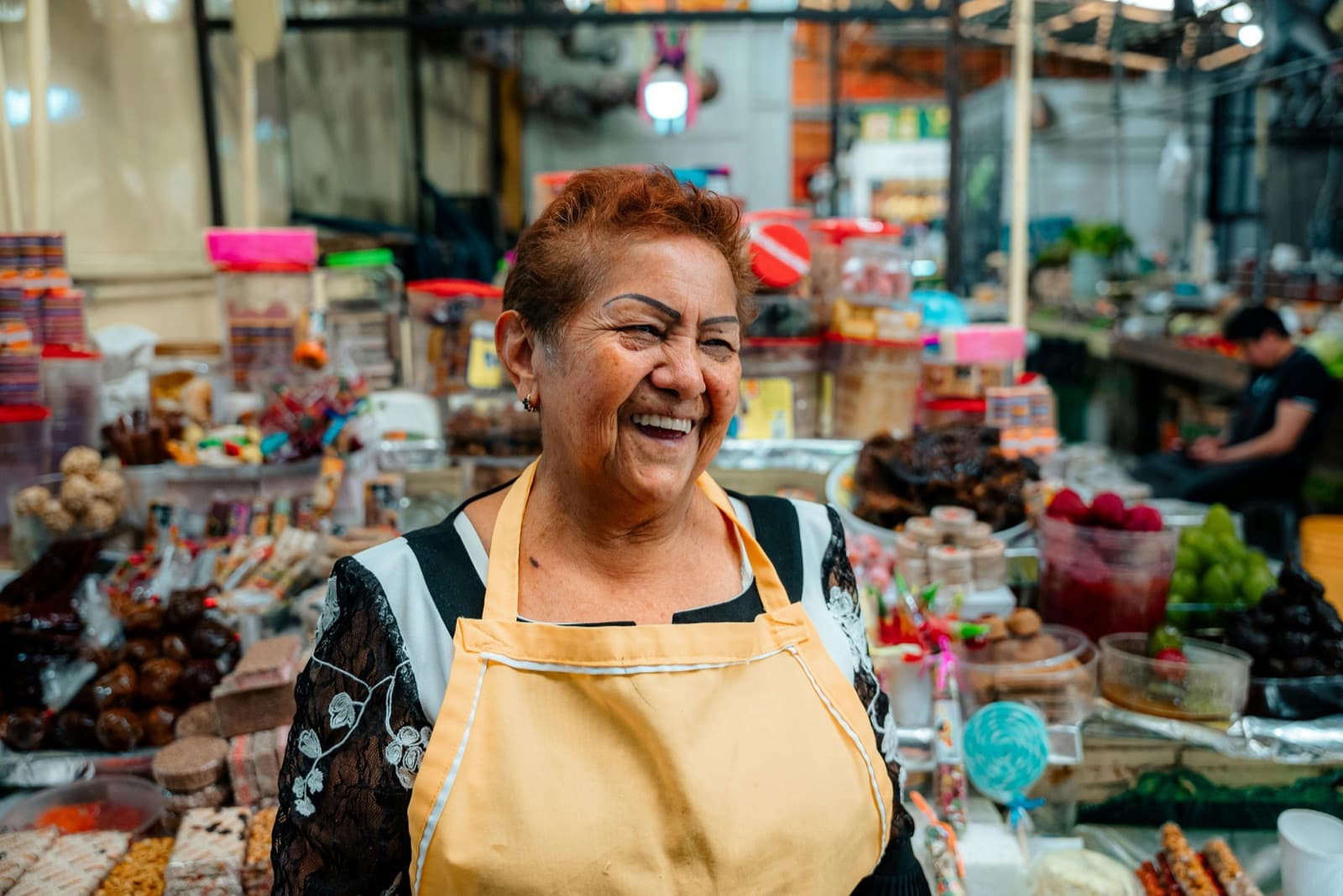Vendedora de dulces típicos sonriendo en su puesto del mercado