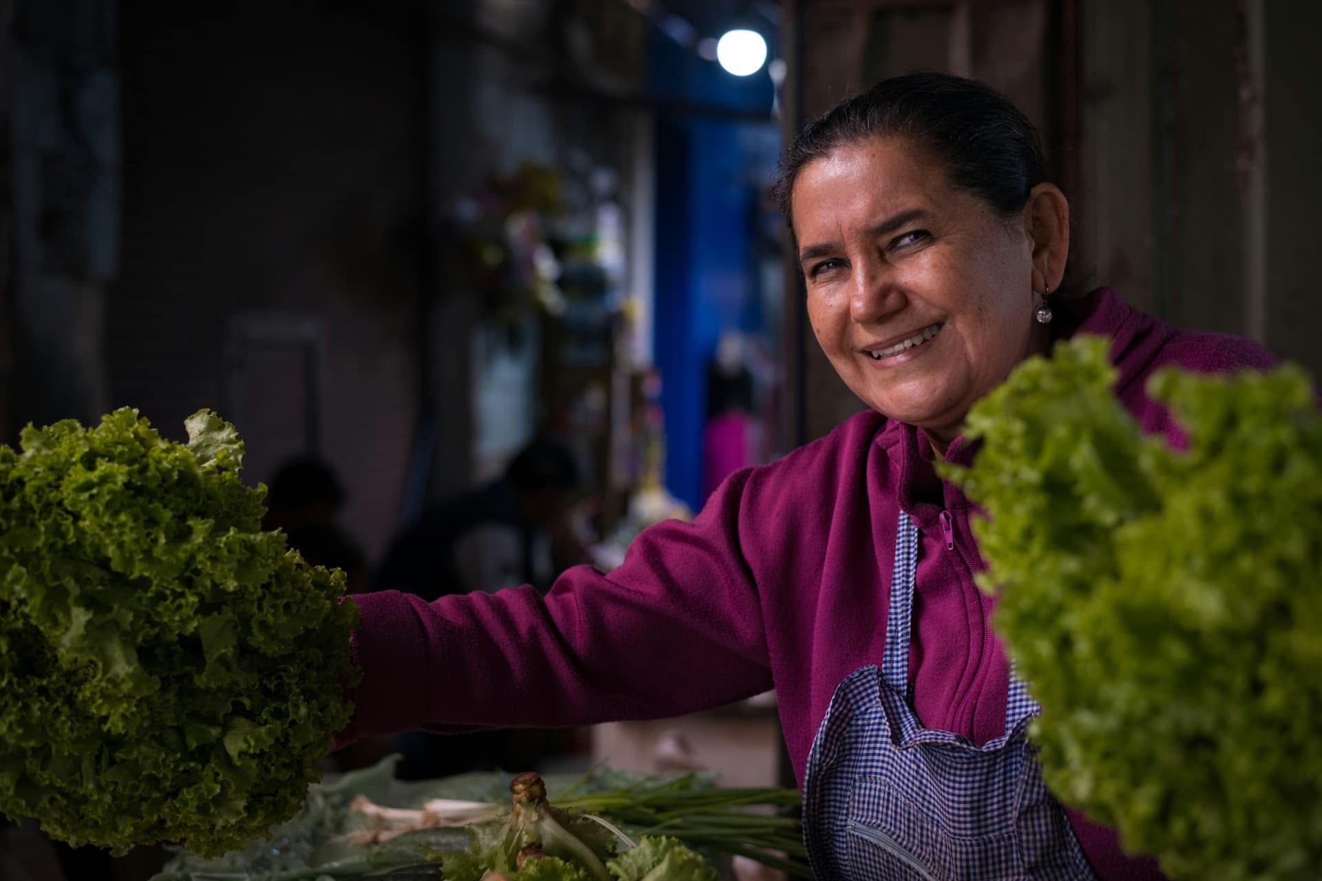 Comerciante mexicana sonriendo en su puesto de verduras